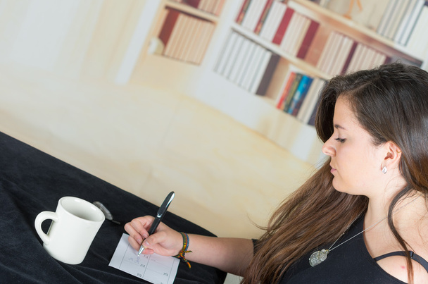 brunette girl sitting and writing on a paper - Fotografie, Obrázek