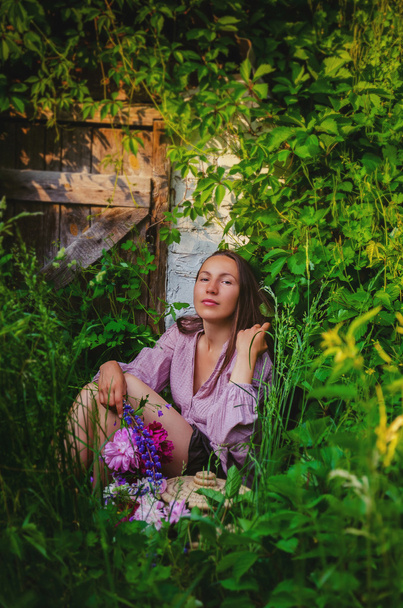 美しい花束と草の茂みで休んでいる優しい女性 - 写真・画像