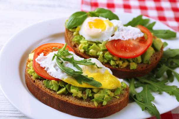 Tasty sandwiches with egg, avocado and vegetables on plate, on wooden background - Zdjęcie, obraz