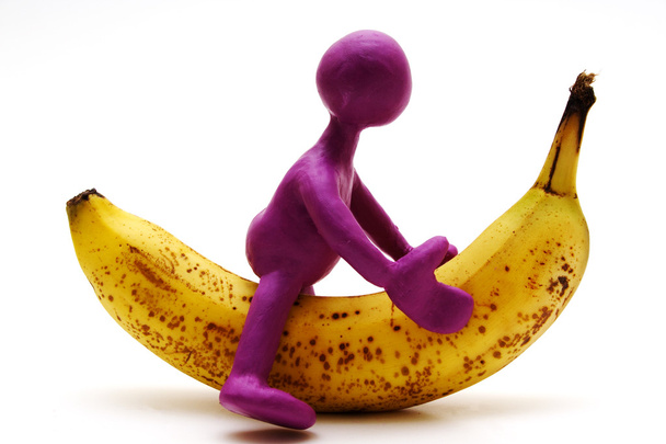 Fantoche roxo de plasticina montando na banana
 - Foto, Imagem