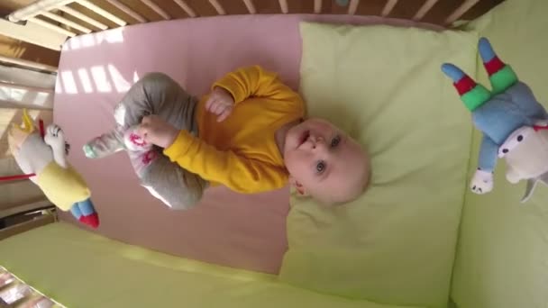 curioso bebé mira carrusel juguete girar sobre la cama. 4K
 - Metraje, vídeo