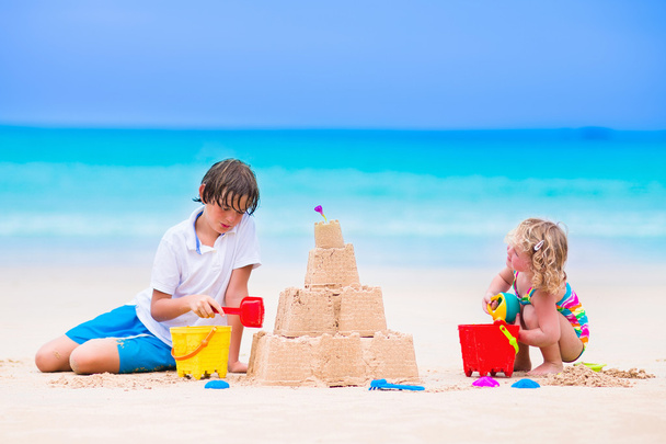Kinderen gebouw zandkasteel op een strand - Foto, afbeelding