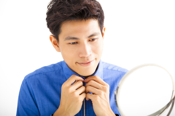 Sonriente hombre guapo arreglando su corbata frente al espejo
 - Foto, Imagen