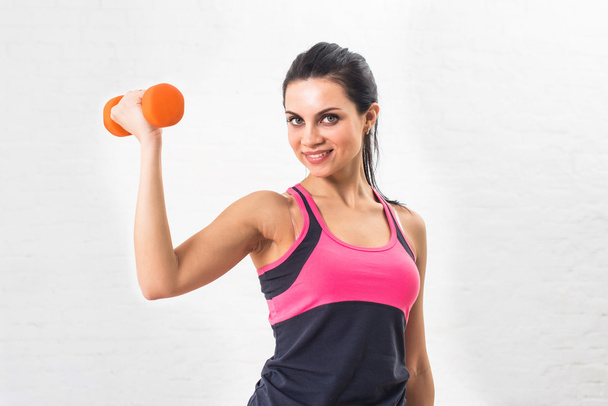 Young woman goes in for sports, fitness with dumbbells. Healthy lifestyle. Health. Shakes hand muscles dumbbells - Foto, Imagen