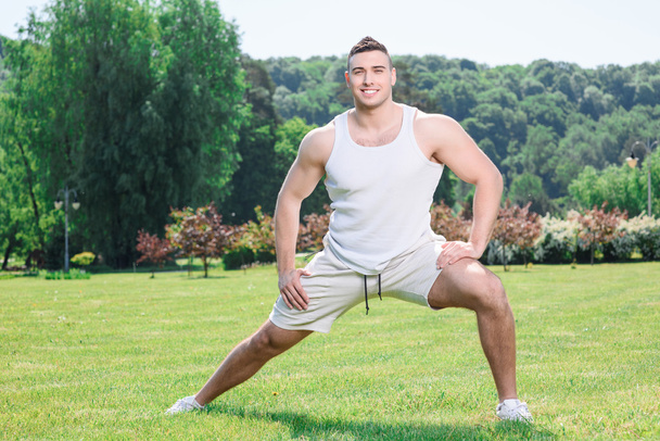 Handsome sportsman doing exercises outdoors - Фото, изображение