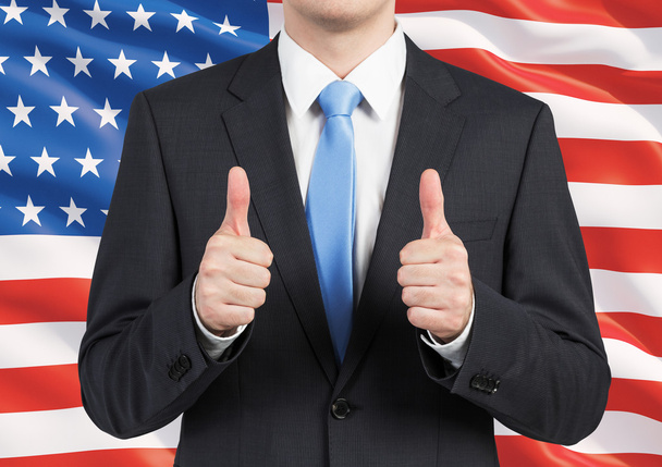 A person in a suit thumbs up. United States flag as a background. - Photo, image
