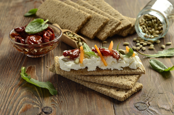 Pane croccante con crema di formaggio, pomodori secchi ed erbe aromatiche
 - Foto, immagini