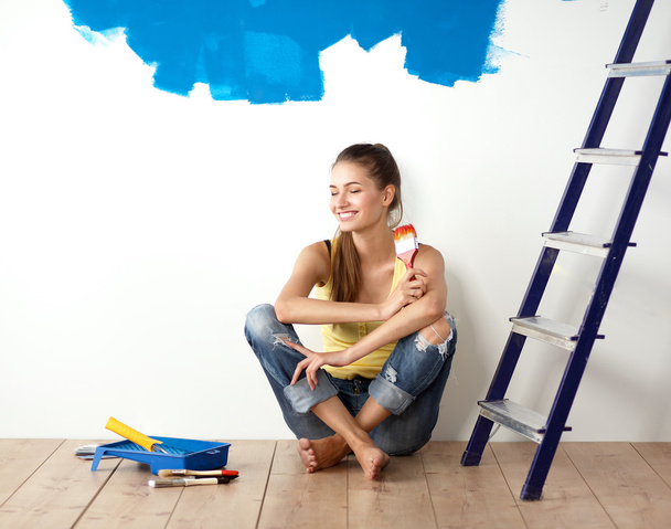 Muotokuva naismaalari istuu lattialla lähellä seinää maalauksen jälkeen
. - Valokuva, kuva