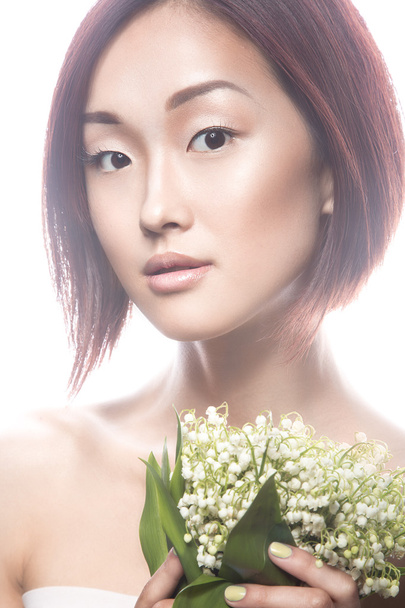 Fashion beautiful girl oriental type with delicate natural make-up and flowers. Beauty face.  - Valokuva, kuva