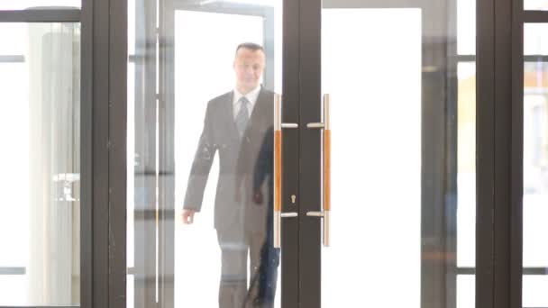 Lächelnder Geschäftsmann im Anzug tritt Tür ein - Filmmaterial, Video