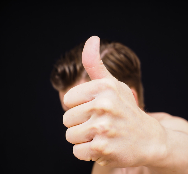 Caucasian male showing thumbs up covering face isolated on black - Foto, afbeelding