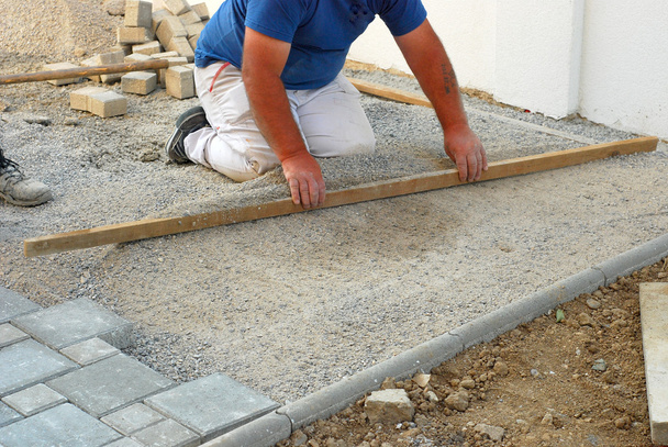 stavební dělník místo vyrovnání písek při instalaci dlažba betonová cihla  - Fotografie, Obrázek