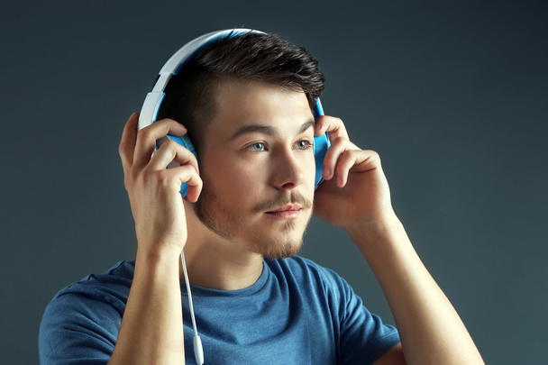 schöner junger Mann hört Musik auf grauem Hintergrund - Foto, Bild