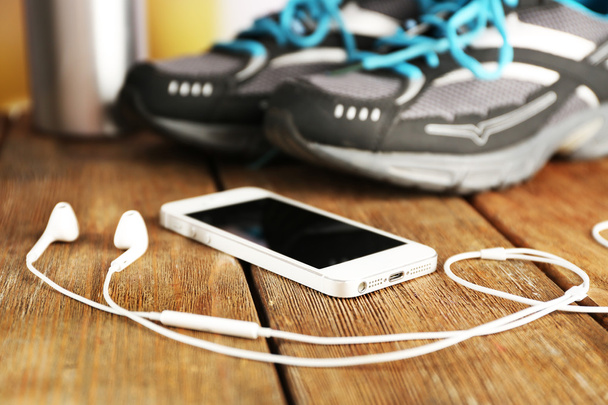 Sneakers and earphones on wooden table, closeup - Photo, Image