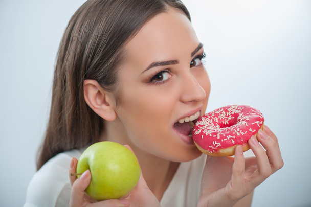 Beautiful young woman with healthy and unhealthy food - Zdjęcie, obraz