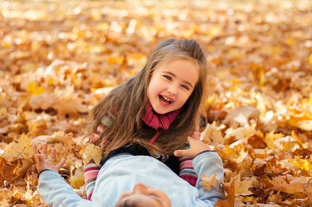 Bambini felici nel parco autunnale sdraiati sulle foglie
 - Foto, immagini