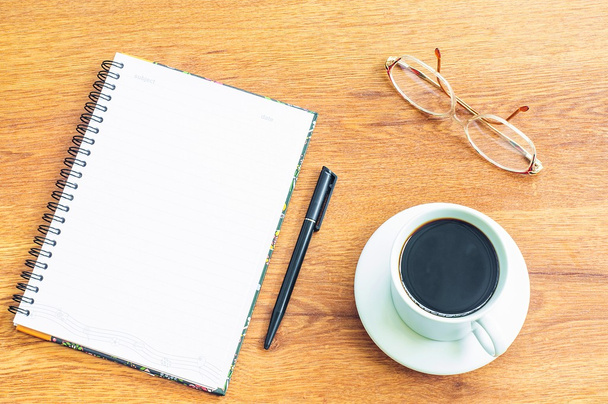 taza de café blanco, vasos, bolígrafo negro, cuaderno sobre fondo de madera
 - Foto, Imagen