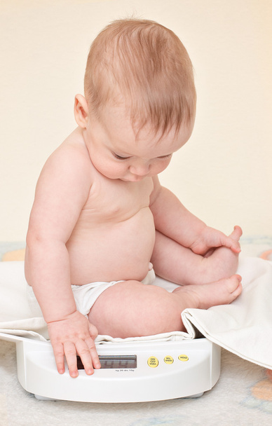 Mignon bébé vérifier son propre poids sur les balances à la maison
 - Photo, image