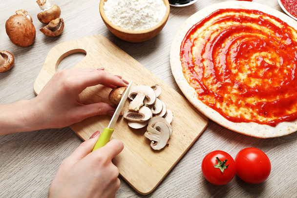 Female hands cooking pizza on wooden table, closeup - Φωτογραφία, εικόνα