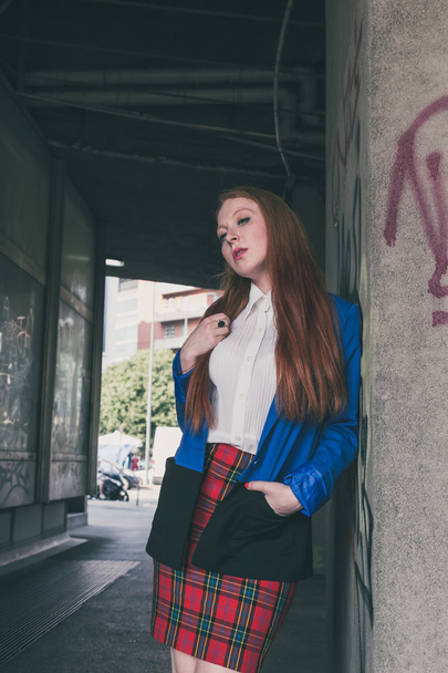 Beautiful redhead girl posing in an urban context - Photo, Image