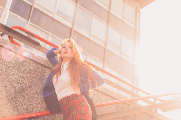 Kaunis punapää tyttö poseeraa kaupunkiympäristössä
 - Valokuva, kuva
