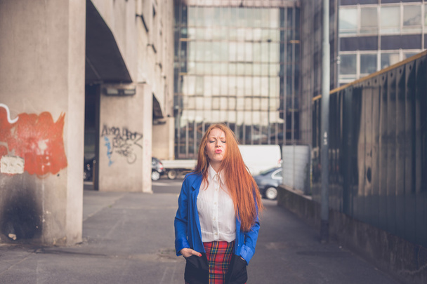 Beautiful redhead girl posing in an urban context - Фото, зображення