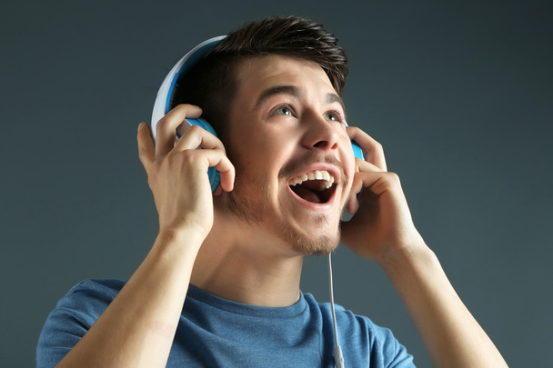 Handsome young man listening to music on grey background - Φωτογραφία, εικόνα