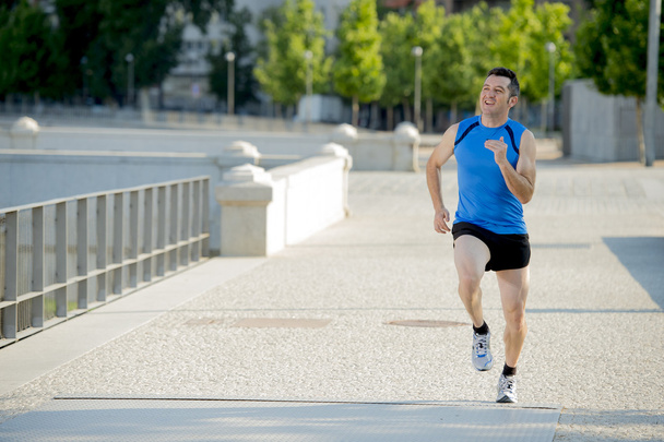 young athletic man running on urban city park in summer sport training session - Photo, Image