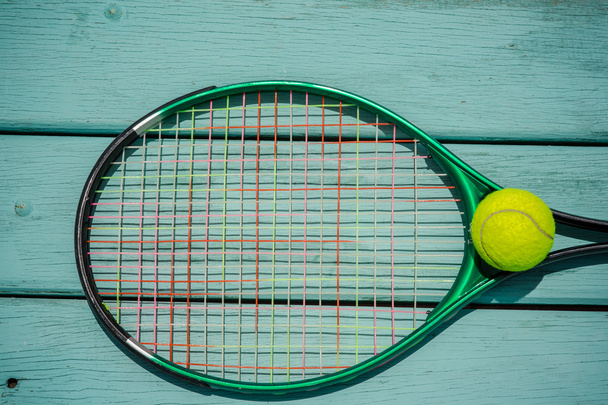 A tennis racket with tennis ball on green wood texture - Φωτογραφία, εικόνα