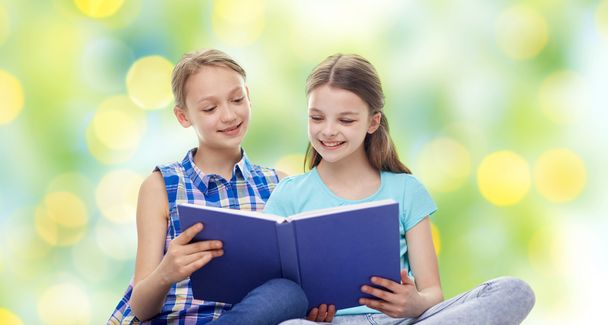 two happy girls reading book over green background - Φωτογραφία, εικόνα