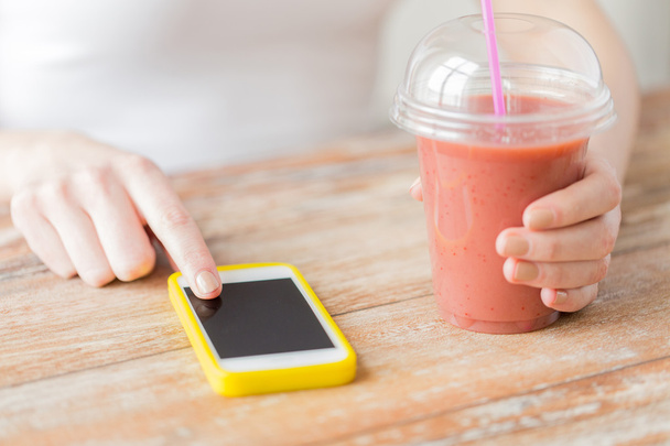 close up of woman with smartphone and smoothie - 写真・画像