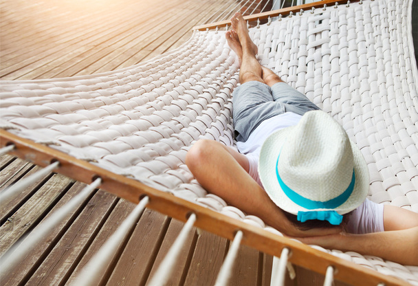 Hombre con sombrero en una hamaca en un día de verano
 - Foto, Imagen