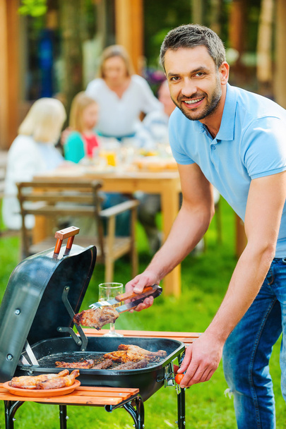 young man barbecuing meat on grill - Zdjęcie, obraz