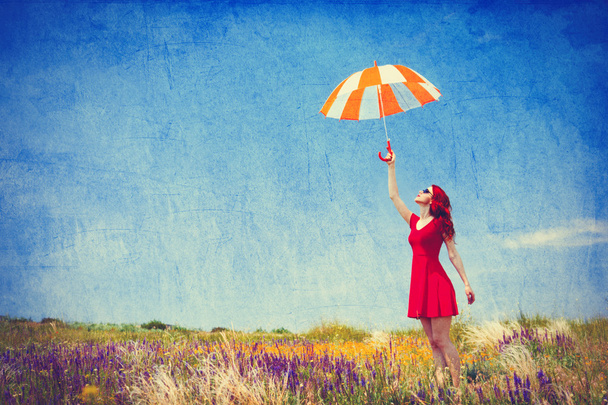 Mulher de vestido vermelho com guarda-chuva no prado
 - Foto, Imagem