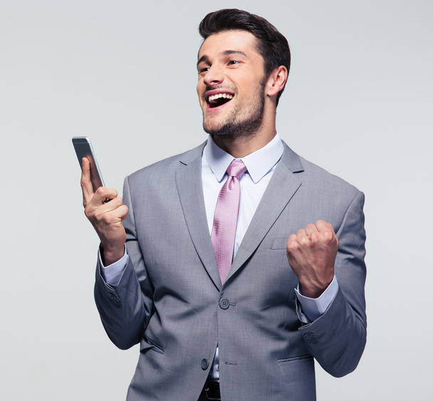 Cheerful businessman holding smartphone - Foto, afbeelding