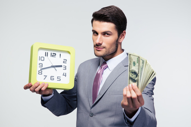 Businessman holding money and clock - Foto, afbeelding