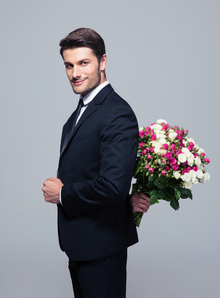 Businessman hiding bouquet of flowers behind his back - Fotoğraf, Görsel
