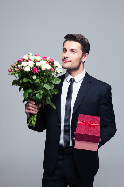 Businessman holding flowers and gift box - Фото, зображення