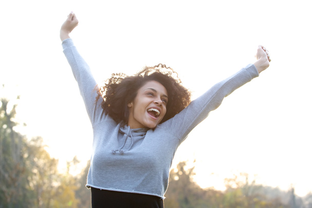 Carefree young woman smiling with arms raised - Photo, Image