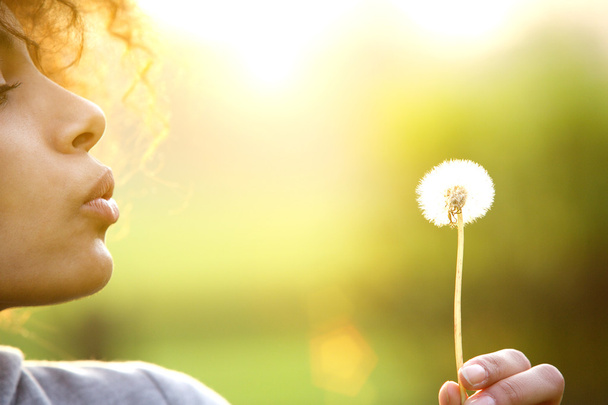 Молодая женщина дует цветок одуванчика на открытом воздухе
 - Фото, изображение