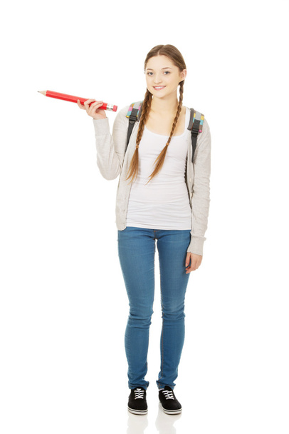 Schoolgirl pointing aside with pencil. - Фото, зображення