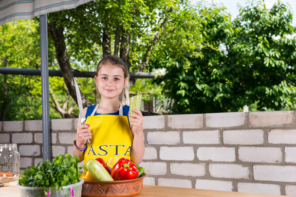 Дівчина з великими ножем за столом з овочами - Фото, зображення