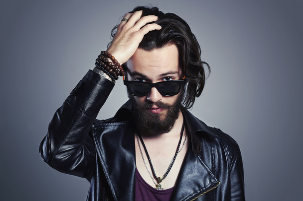 fashionable handsome man in a leather jacket. Brutal bearded Sexy boy in trendy sunglasses.rock and roll - Fotó, kép