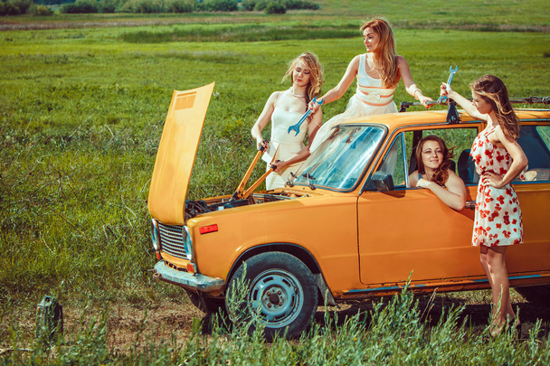 Hermosas mujeres con herramientas están reparando un coche en la carretera rural
 - Foto, Imagen