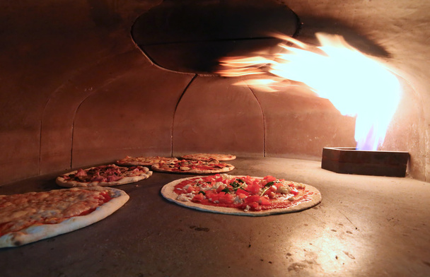 Pizza no forno com a chama quente
 - Foto, Imagem