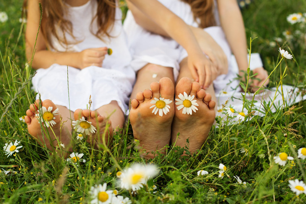 Two pair of childs feets with daisy flowers  - Photo, Image
