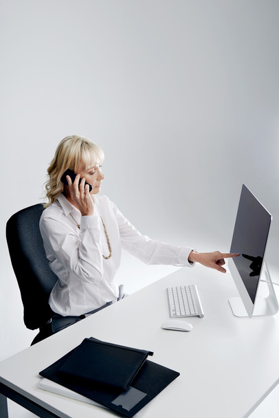 woman at desk talking on cellphone - Foto, Bild