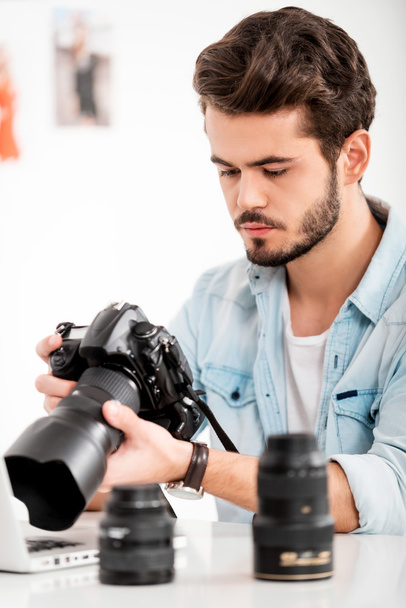 Serious young man holding camera - Fotó, kép