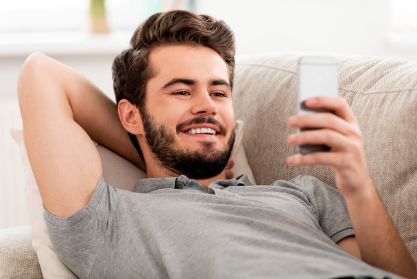 Smiling bearded man holding mobile phone - Foto, afbeelding
