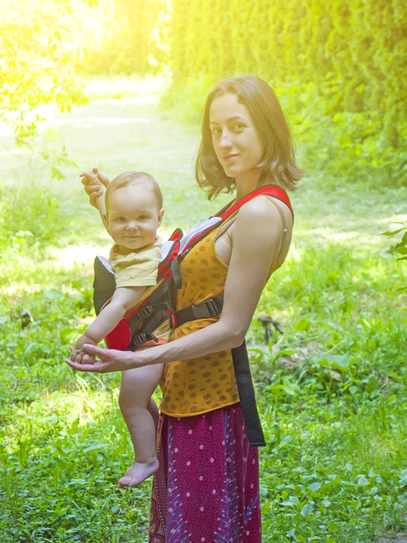 Μια νεαρή μητέρα στην Ανατολική φόρεμα, κρατώντας ένα μικρό παιδί σε ένα μωρό - Φωτογραφία, εικόνα